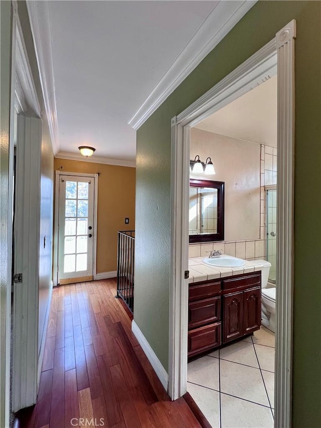 hallway featuring sink, light hardwood / wood-style flooring, and crown molding