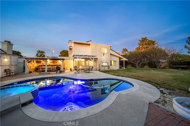 pool at dusk with a patio, a yard, and an in ground hot tub