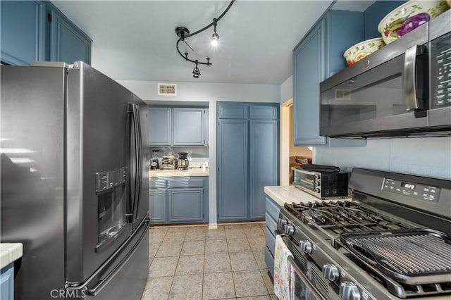 kitchen with light tile patterned floors, blue cabinets, and stainless steel appliances