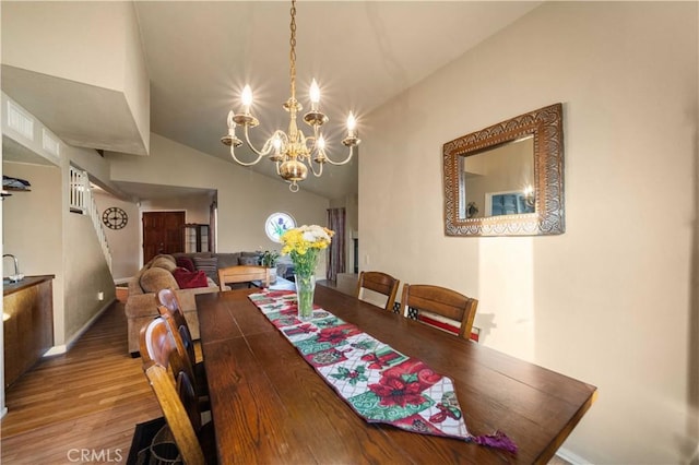 dining area with wood-type flooring, a chandelier, and vaulted ceiling