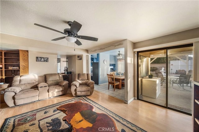 living room featuring ceiling fan, a textured ceiling, and light hardwood / wood-style flooring