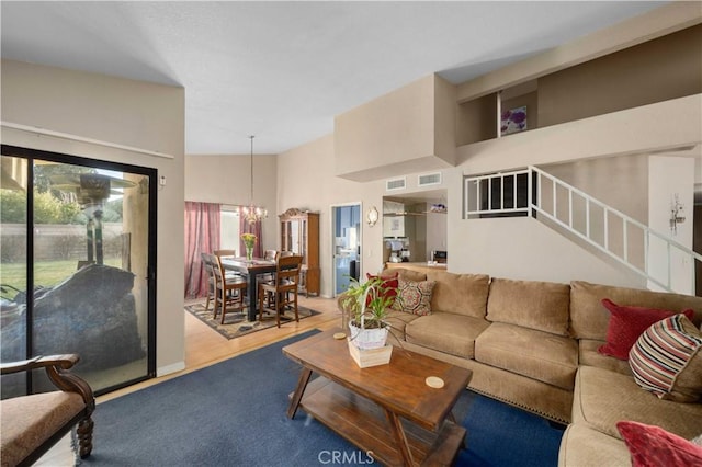 living room with a chandelier, wood-type flooring, and high vaulted ceiling