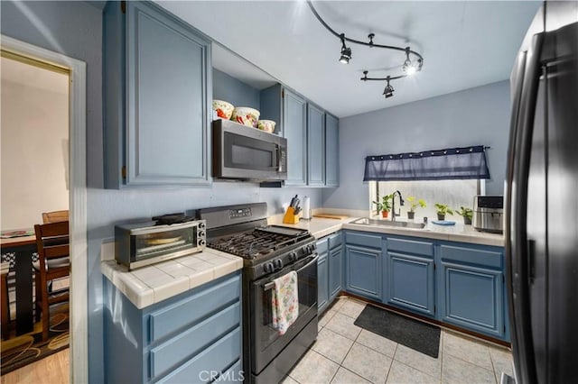 kitchen featuring tile counters, blue cabinetry, light tile patterned flooring, black appliances, and sink