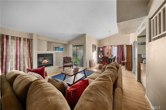 living room featuring an inviting chandelier, lofted ceiling, and light wood-type flooring