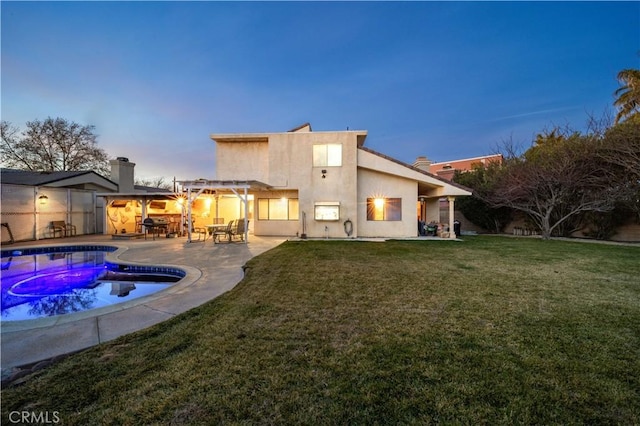 back house at dusk with a patio, a lawn, and a pergola