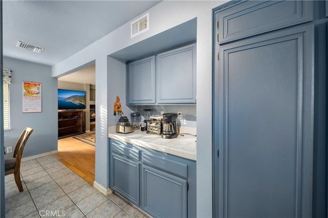 kitchen featuring blue cabinetry, light tile patterned floors, and tile counters