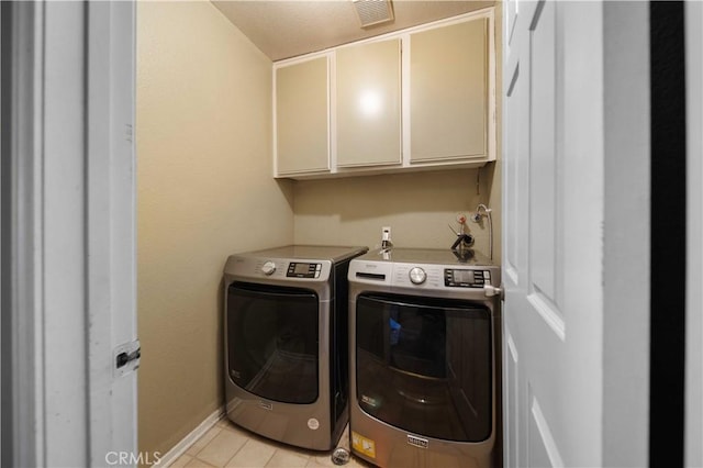 laundry area with washer and dryer, cabinets, and light tile patterned flooring