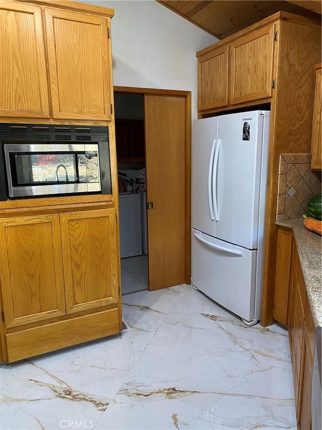 kitchen featuring white refrigerator, decorative backsplash, and independent washer and dryer