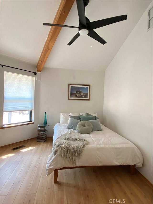 bedroom featuring a ceiling fan, visible vents, vaulted ceiling with beams, and light wood-style floors