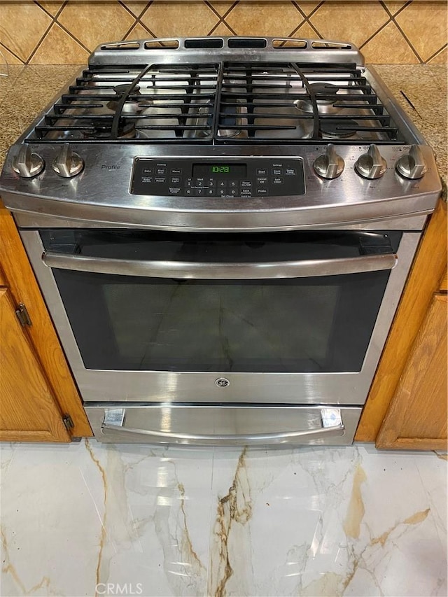 details with decorative backsplash and stainless steel range with gas stovetop