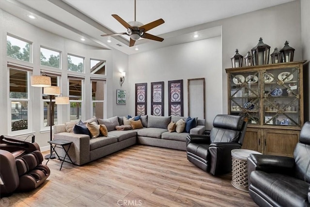 living room with ceiling fan, light hardwood / wood-style floors, and a high ceiling