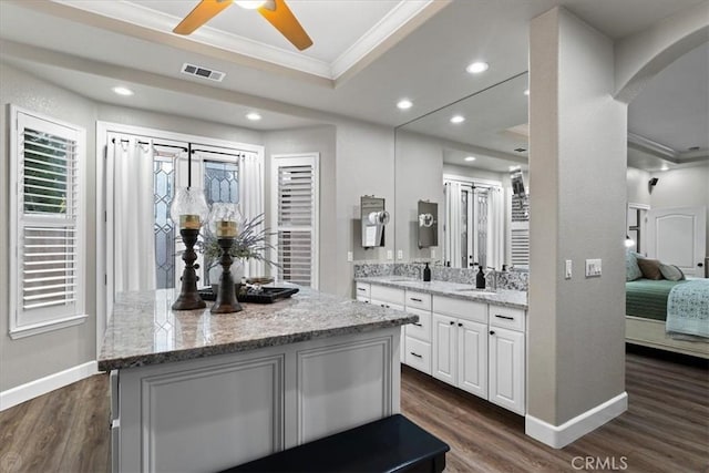 kitchen featuring light stone countertops, white cabinetry, dark hardwood / wood-style flooring, and ornamental molding