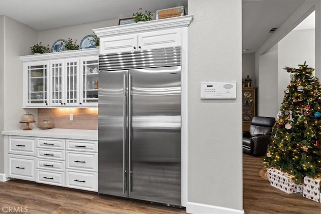 kitchen featuring dark wood-type flooring, white cabinetry, stainless steel built in fridge, and tasteful backsplash