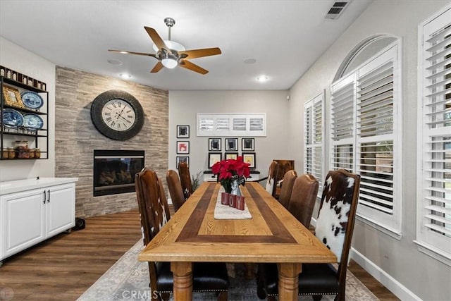 dining space with ceiling fan, a fireplace, and dark hardwood / wood-style flooring