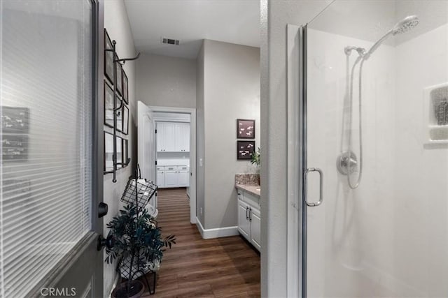 bathroom with a shower with shower door, hardwood / wood-style floors, and vanity