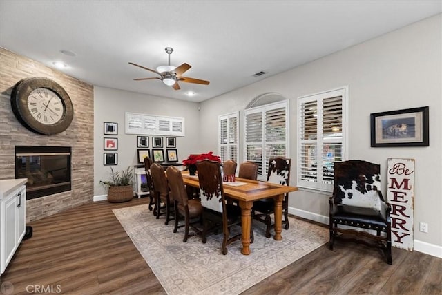 dining room featuring hardwood / wood-style flooring, ceiling fan, and a fireplace