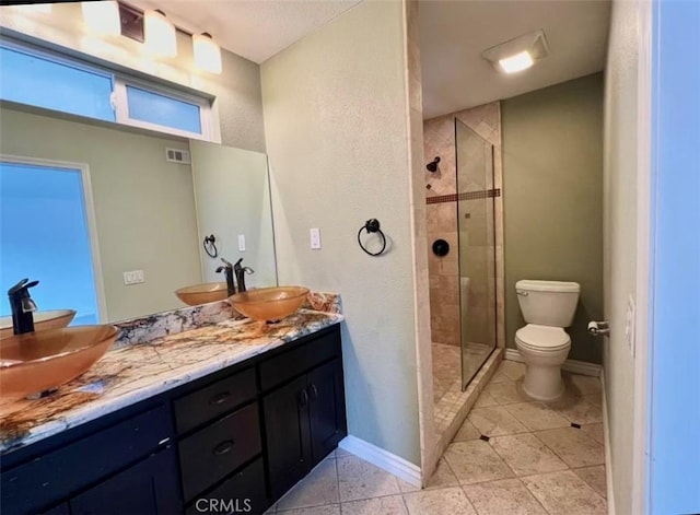 bathroom featuring vanity, toilet, and a tile shower