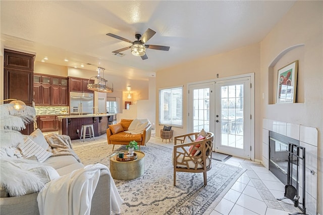 tiled living room with a tile fireplace, french doors, and ceiling fan