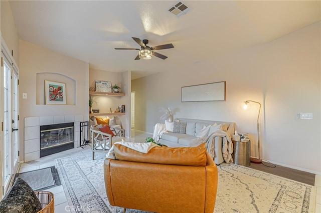 living room featuring a tile fireplace and ceiling fan