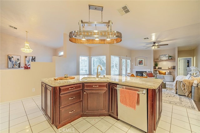 kitchen featuring sink, decorative light fixtures, stainless steel dishwasher, and a center island with sink