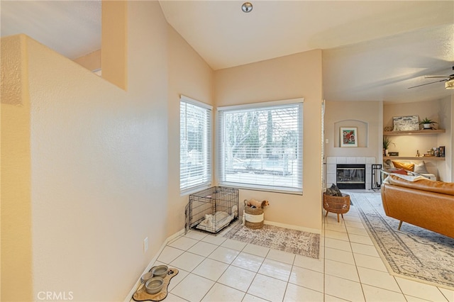 interior space featuring tile patterned flooring, ceiling fan, vaulted ceiling, and a fireplace