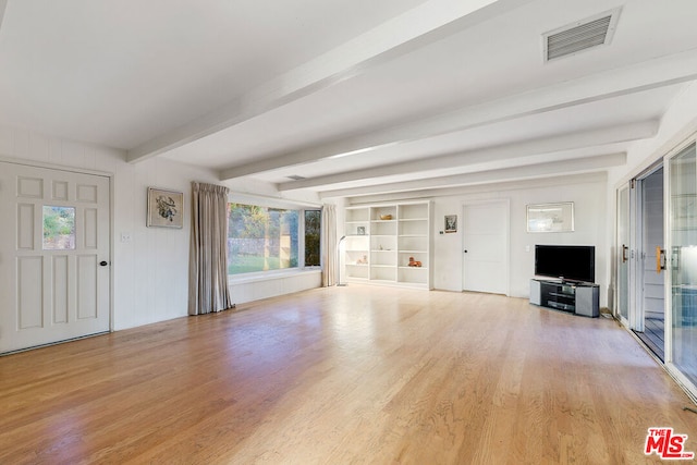 unfurnished living room featuring built in shelves, beamed ceiling, and light hardwood / wood-style flooring