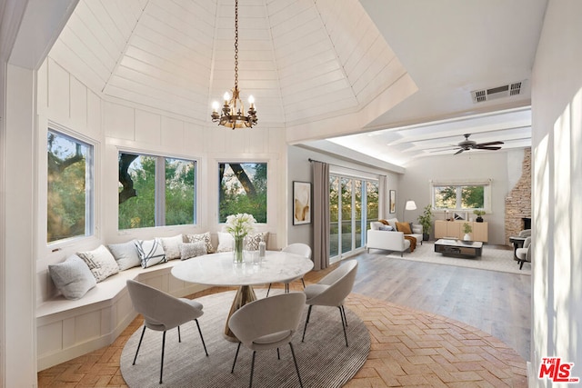 sunroom / solarium featuring ceiling fan with notable chandelier and vaulted ceiling