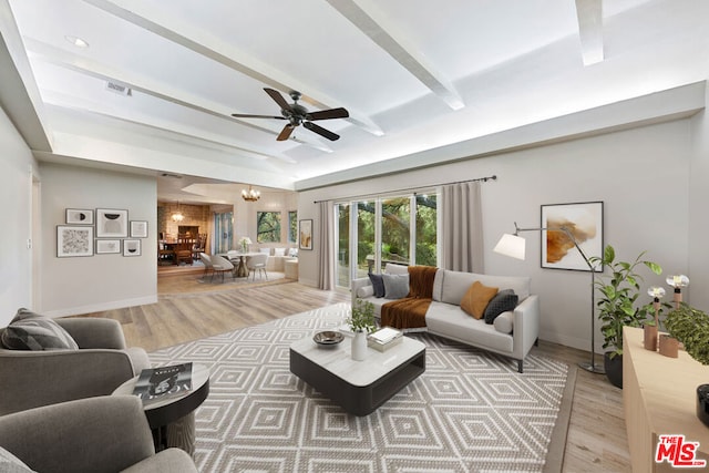 living room with light wood-type flooring, ceiling fan with notable chandelier, and beam ceiling