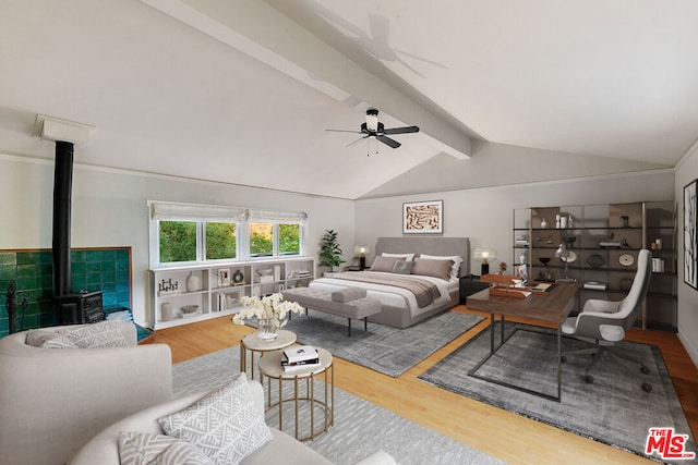 bedroom with ceiling fan, a wood stove, wood-type flooring, and lofted ceiling with beams