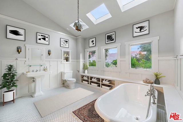 bathroom featuring toilet, vaulted ceiling with skylight, and a tub to relax in