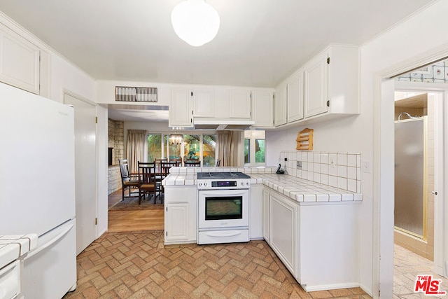 kitchen featuring tile counters, white cabinets, tasteful backsplash, and white appliances