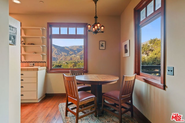 dining area featuring a mountain view, light hardwood / wood-style flooring, and a chandelier