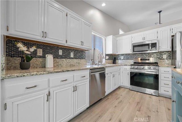 kitchen featuring white cabinetry, stainless steel appliances, sink, backsplash, and light hardwood / wood-style flooring