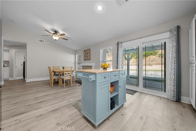 kitchen featuring vaulted ceiling, wood counters, blue cabinetry, and a center island