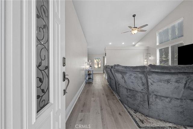 unfurnished living room with ceiling fan, vaulted ceiling, and light hardwood / wood-style flooring