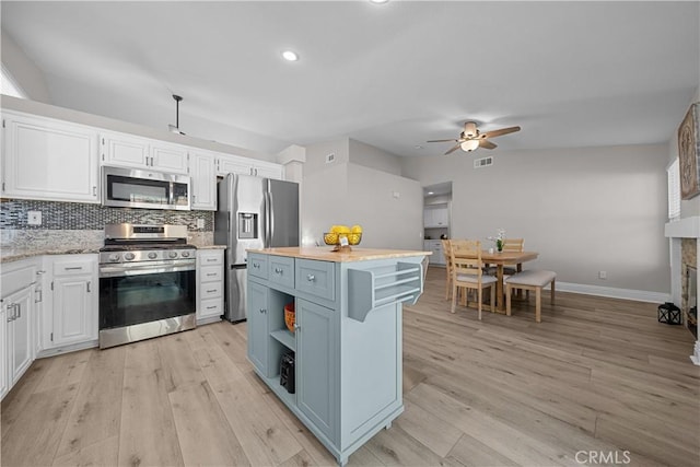 kitchen featuring ceiling fan, backsplash, a center island, white cabinetry, and stainless steel appliances