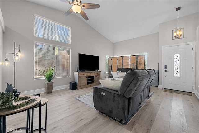 living room with ceiling fan with notable chandelier, high vaulted ceiling, and light wood-type flooring