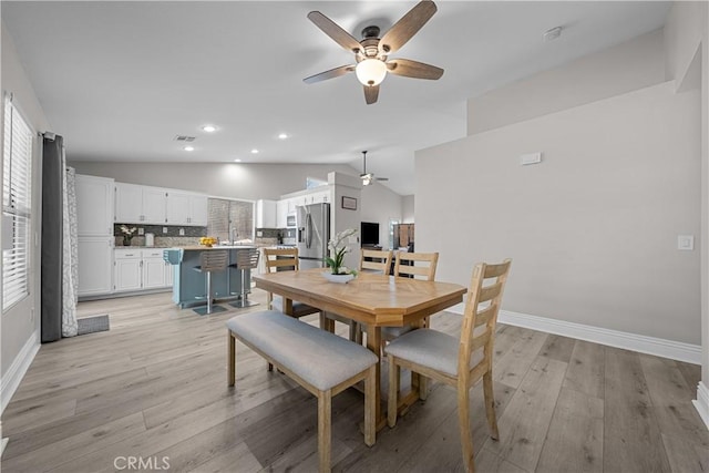 dining space featuring ceiling fan, light wood-type flooring, sink, and lofted ceiling