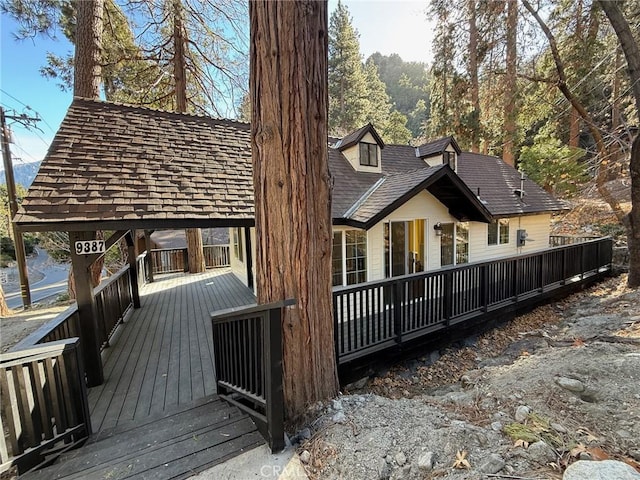 exterior space with roof with shingles and a wooden deck