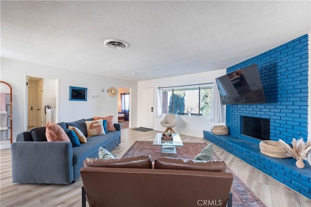 living room with a fireplace, a textured ceiling, and light hardwood / wood-style floors