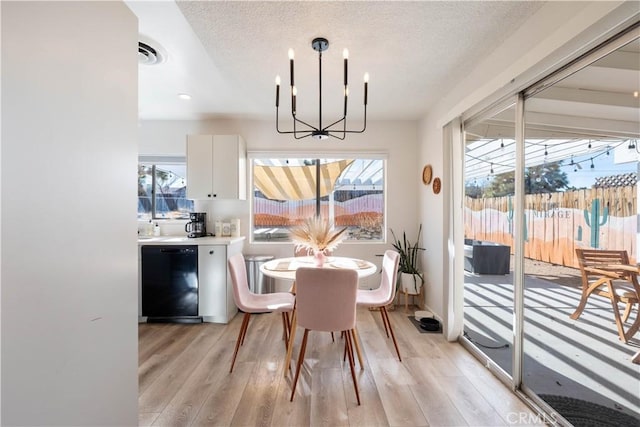 dining area with a textured ceiling, light hardwood / wood-style flooring, and a chandelier