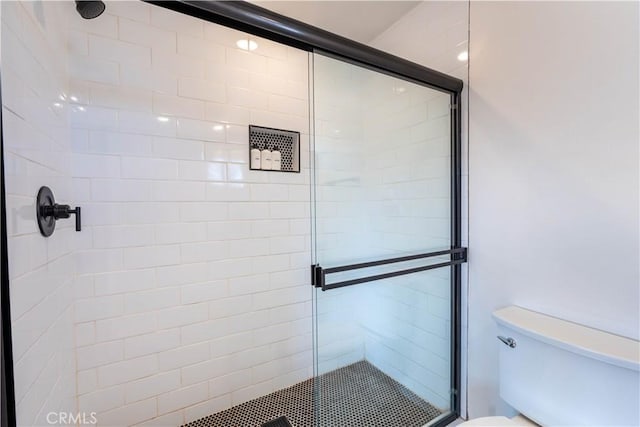 bathroom with toilet and a shower with door