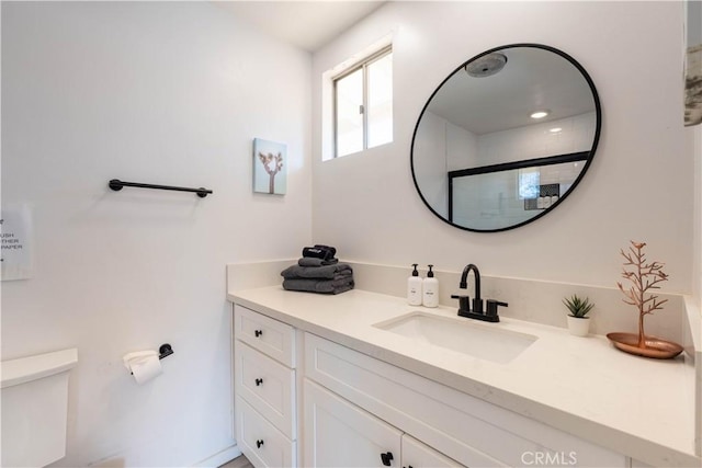 bathroom with toilet, vanity, and a shower with door