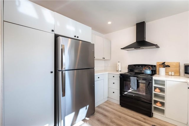 kitchen featuring white cabinetry, light hardwood / wood-style floors, wall chimney range hood, black range with electric cooktop, and stainless steel refrigerator