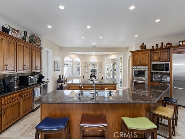 kitchen with a breakfast bar, a center island with sink, built in appliances, and a sink