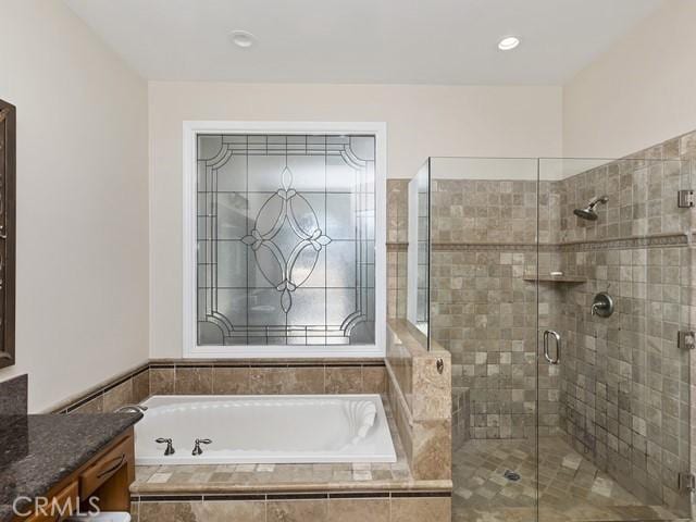 full bath featuring vanity, a garden tub, and a shower stall