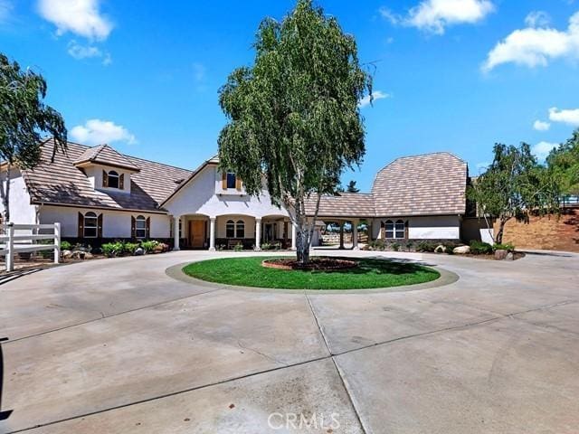 view of front facade with stucco siding and curved driveway