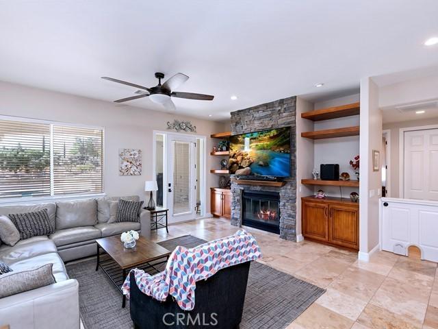 living area with a stone fireplace, recessed lighting, baseboards, and ceiling fan