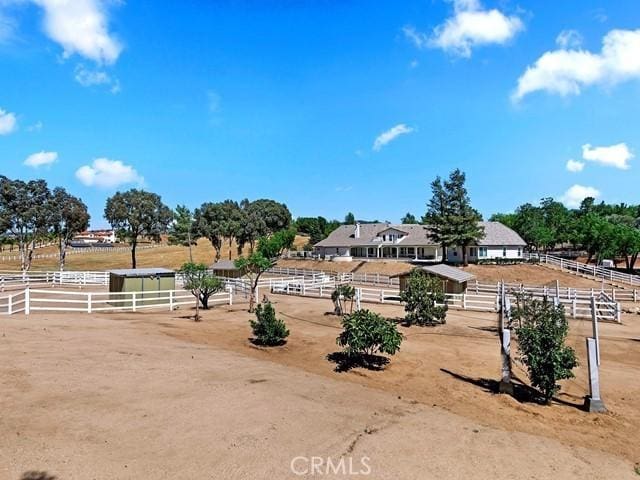 view of yard featuring an enclosed area, a rural view, and fence