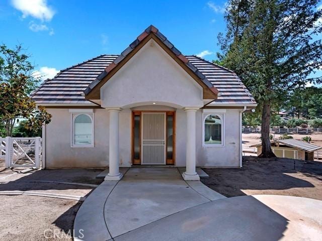 view of front of house with a tiled roof, fence, and stucco siding